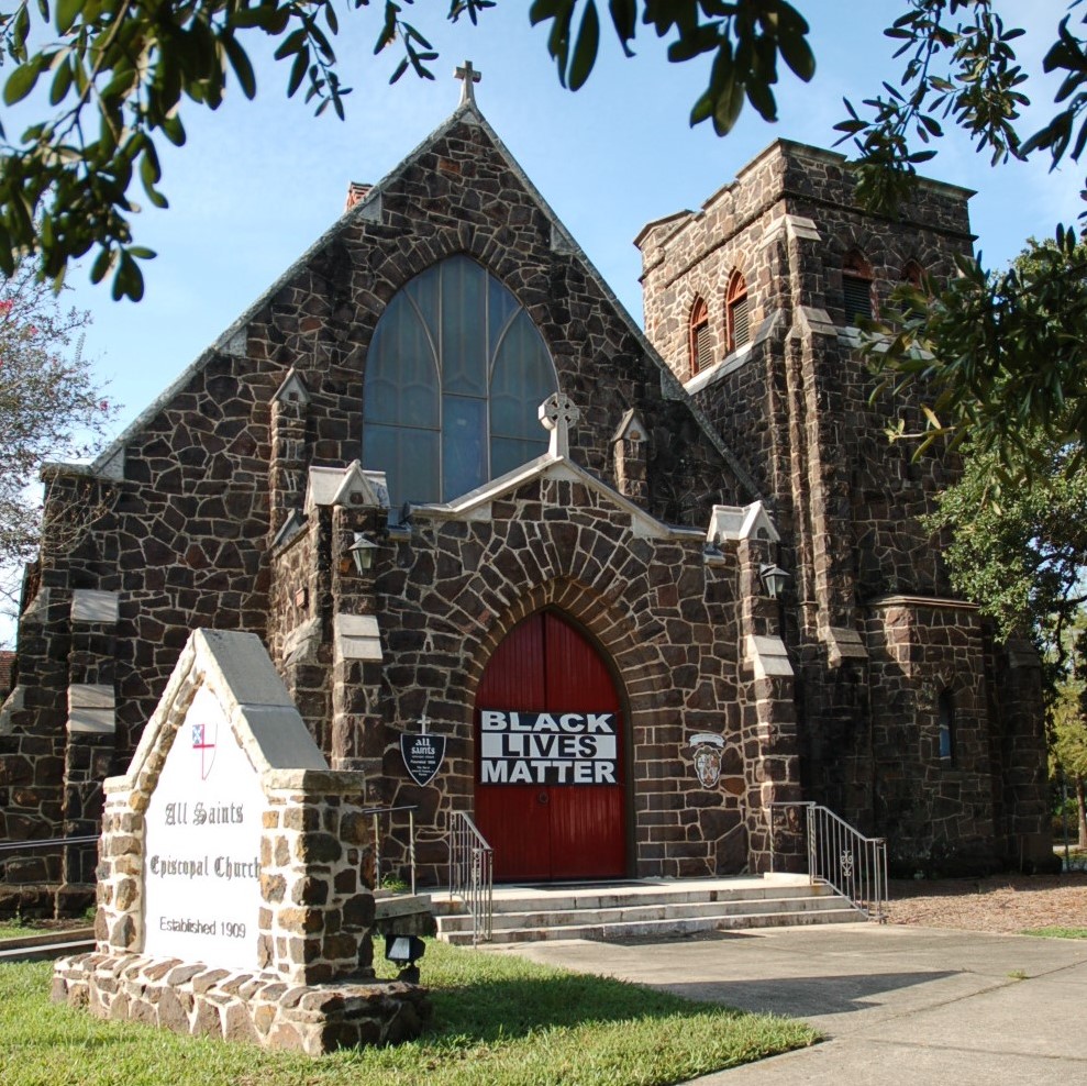 dark sandstone church with Black Lives Matter banner on front doors