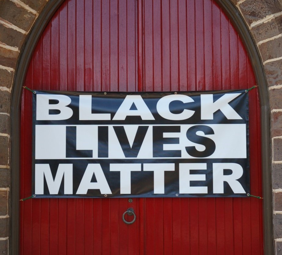 Black Lives Matter banner over red church doors