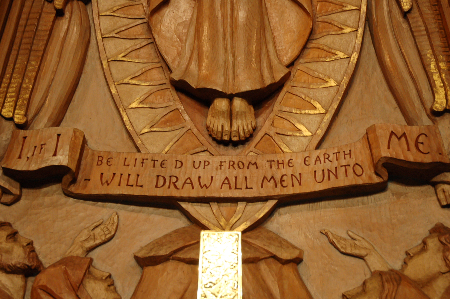 center of carved wood reredos above altar: the feet of Jesus with words "I, if I be lifted up from the earth, will draw all men unto Me."