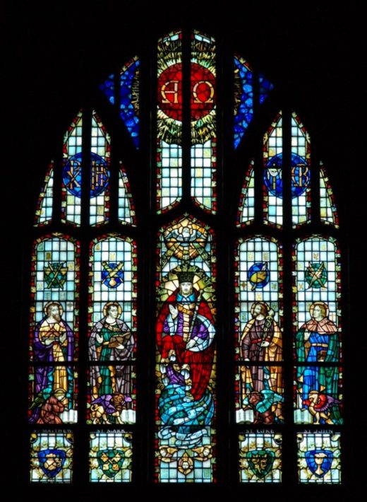 Large stained-glass window with five men and various Christian religious symbols surrounding them