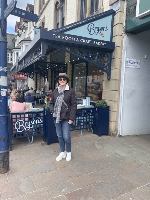 woman standing on sidewalk in front of a tea room