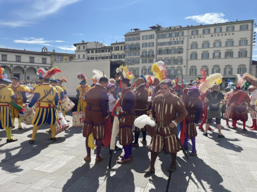 several men dressed in Renaissance-style clothing in an open city square
