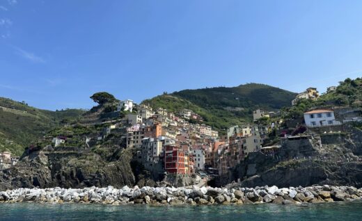 houses clinging to steep cliffs near the sea, with a blue sky overhead