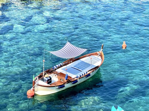 a wooden boat sits at anchor in clear, aqua-colored water