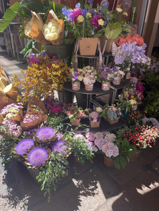 tiered display of a variety of flowers for sale in front of a shop