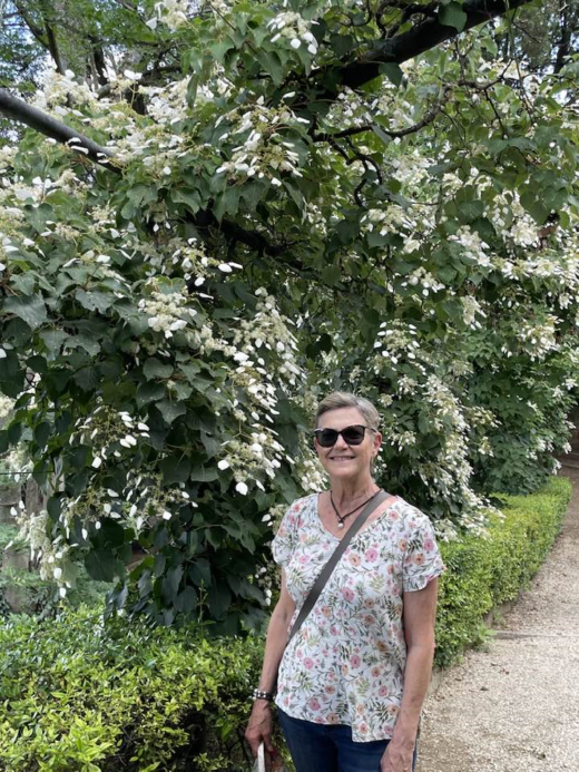 woman standing in front of a climbing plant with white flowers