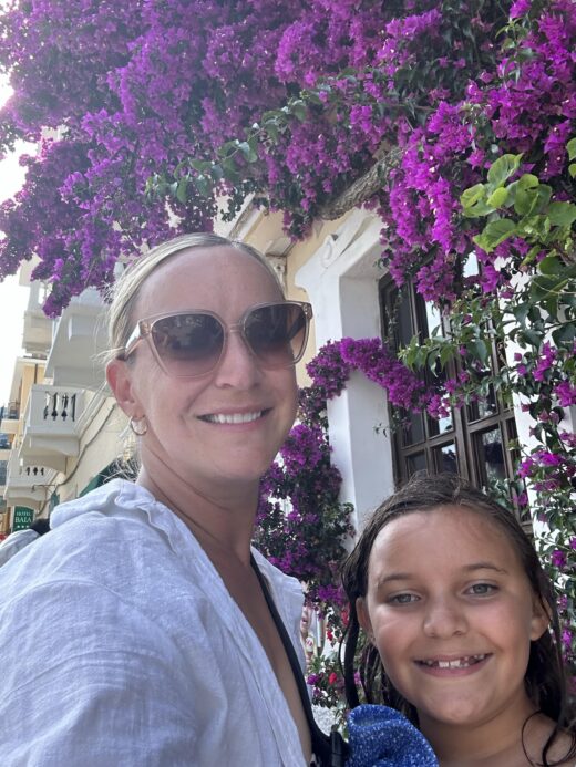 a woman and child in front of a building with flowering plants hanging off of it